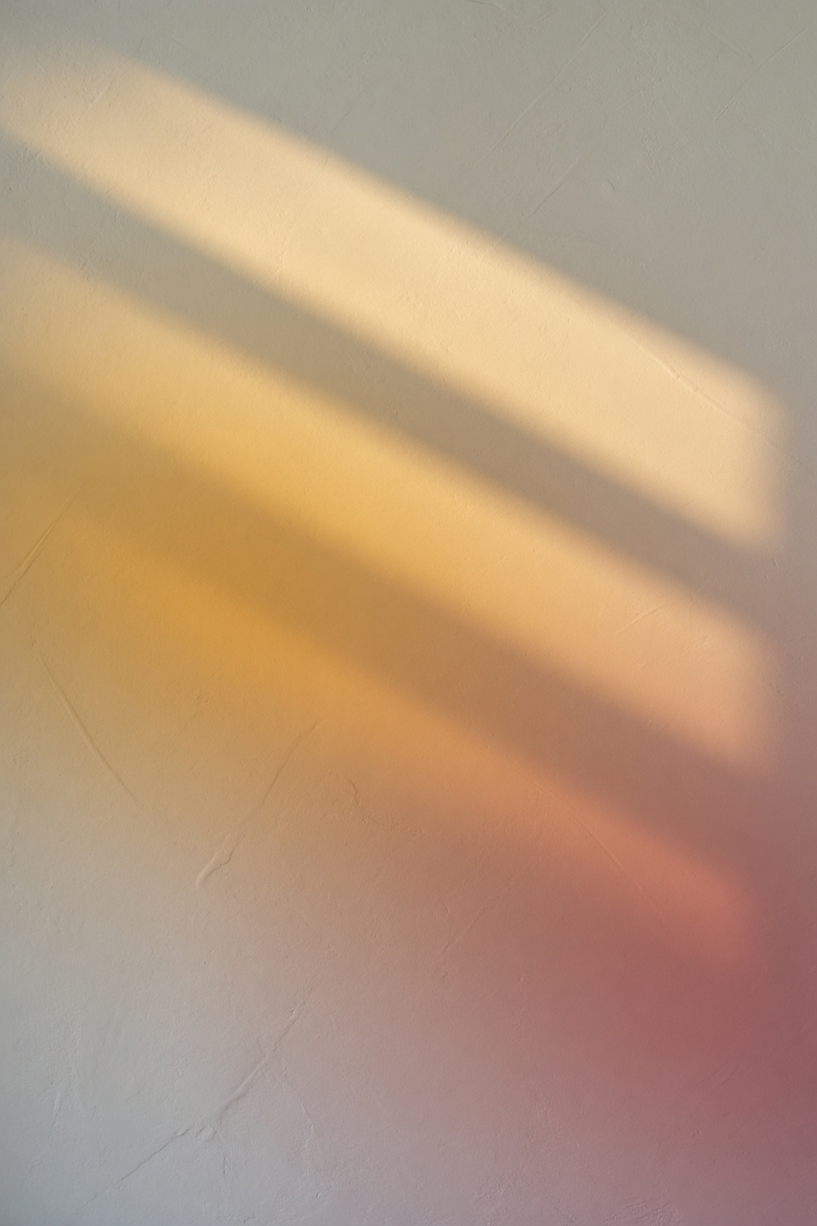 Lumière du jour glissant de l'or au rose sur un mur clair